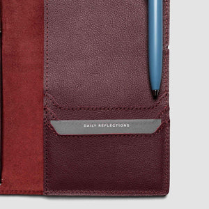 Close-up of a leather-bound journal with a pen pocket and 'Daily Reflections' label.