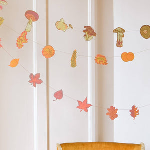 Decorative wall stickers of mushrooms and leaves on a white wall with a chair in the foreground.