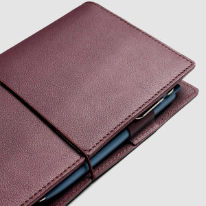 Brown leather wallet with a pen holder on a light gray background