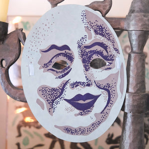 Decorative mask with purple accents on a decorative stand