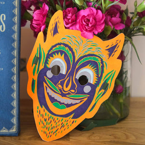 Colorful mask on a wooden surface with flowers in the background