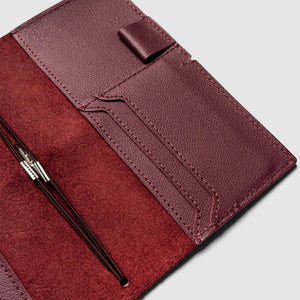 Maroon leather wallet with a pen on a light gray background