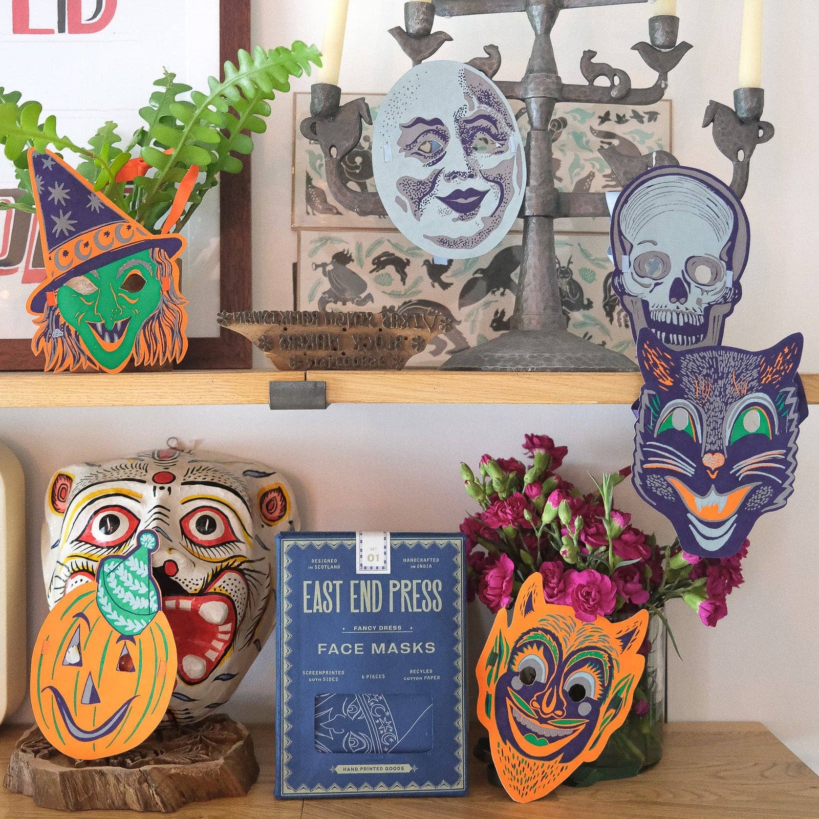 Decorative shelf with Halloween-themed masks and candles